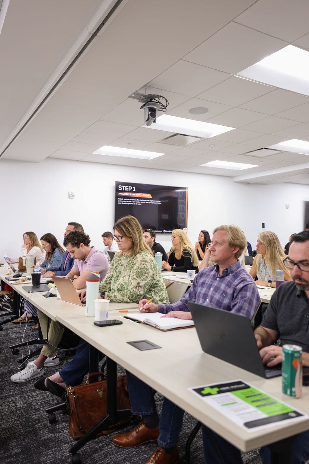 Agents taking notes during a live coaching session in an office classroom