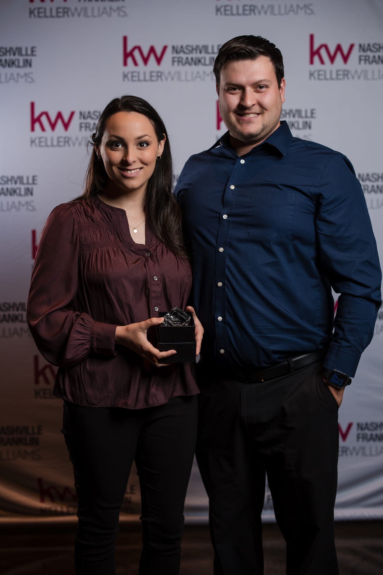 An agent duo accepting a crystal production award at the Franklin market center's annual celebration