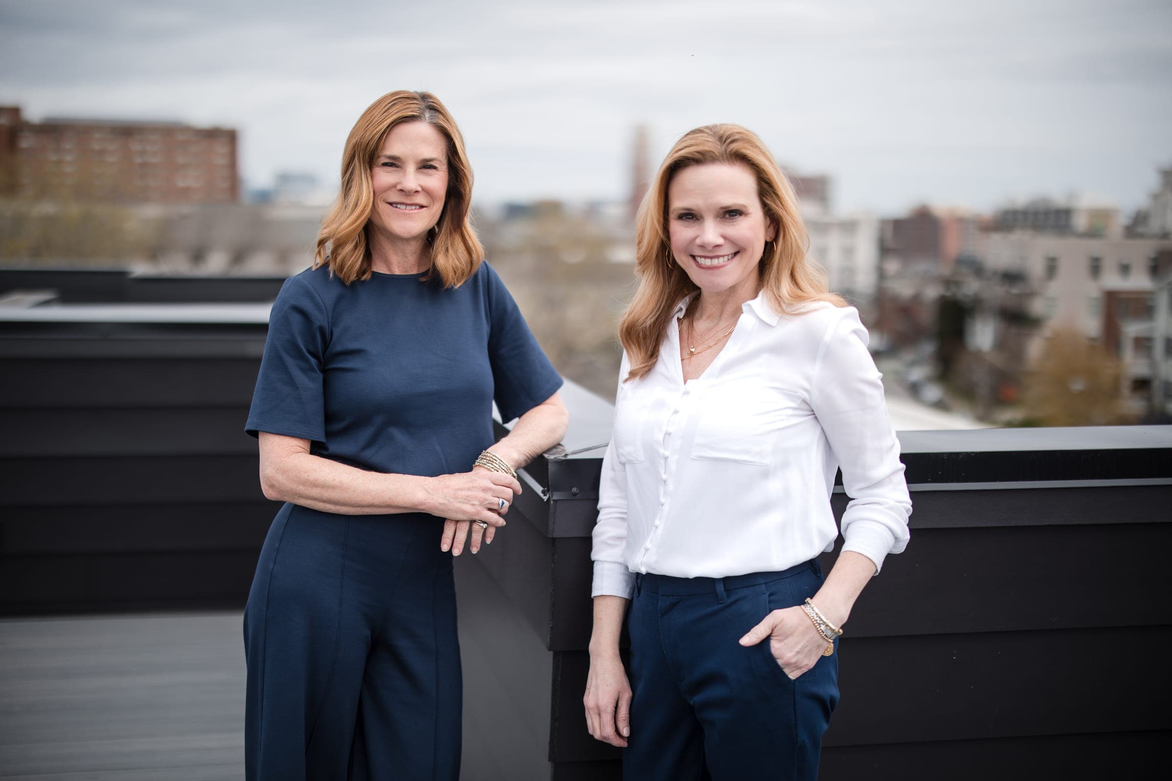 Two Empower agents standing together on a rooftop above Nashville, the Midtown skyline behind them under an overcast sky