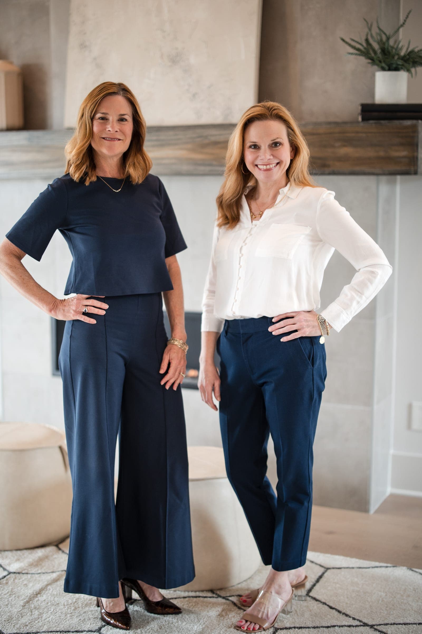 Two Middle Tennessee agents standing together in a staged living room with a linear fireplace and reclaimed-wood mantel